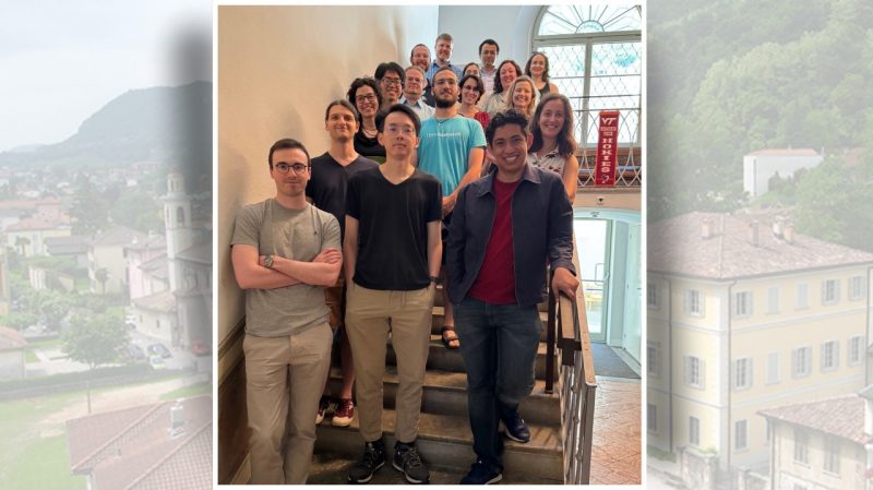 A group of diverse students and faculty pose together on a staircase inside a bright building at the Steger Center for International Scholarship, Virginia Tech. A banner reading 'VT Invent the Future Hokies' is visible beside them, and a window behind them lets in natural light. Everyone is smiling. The Virginia Tech logo and Steger Center branding appear at the top of the image.